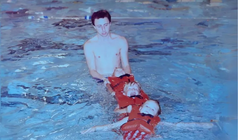 Photo of man teaching swimming lessons to 2 kids in 1980s