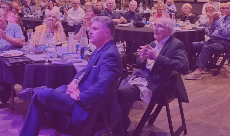 Photo shows group of people at a dinner including Cal Fercho and son in the center.