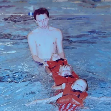 Photo of man teaching swimming lessons to 2 kids in 1980s